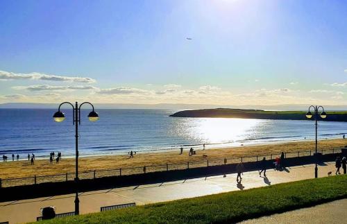 a group of people walking on the beach at Barry Island Beachfront Apartment - Stunning Bay Views and Private Parking in Barry