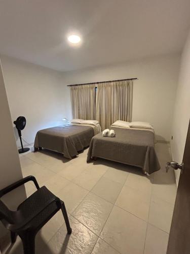 a bedroom with two beds and a chair and a window at Apartamento 201 amplio cómodo in Cali