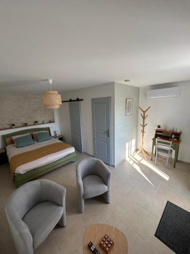 a bedroom with a bed and two chairs and a table at Ô Ptit Verger in Coulon
