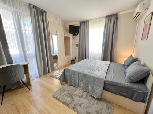 a bedroom with a bed and a desk and windows at House Varna-4 in Krapets