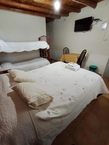 a bedroom with a large bed with white sheets and pillows at Hospedaje Andacollo in Balde del Rosario