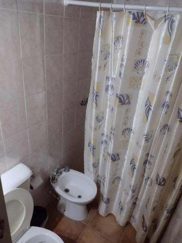 a bathroom with a toilet and a shower curtain at Hospedaje Andacollo in Balde del Rosario