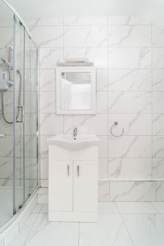 a white bathroom with a sink and a shower at Iveagh Lodge in Dublin