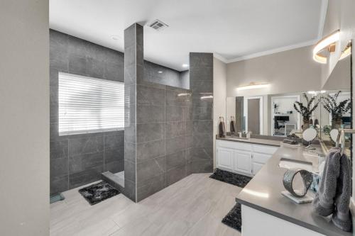 a bathroom with a shower and a sink and a mirror at The Tulsacation on Oxford in Tulsa