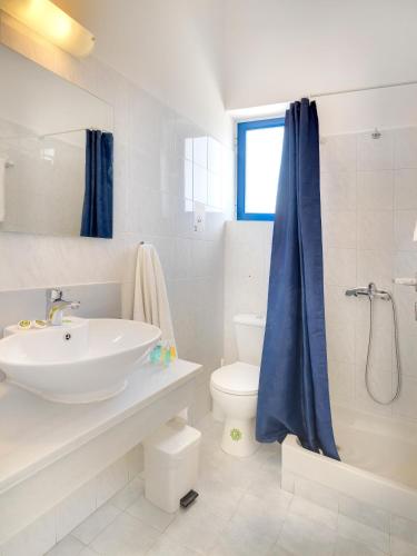 a white bathroom with a sink and a toilet at Hotel Kamelo in Vari