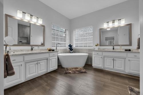 a white bathroom with two sinks and a bath tub at The Tulsacation 2 in Tulsa