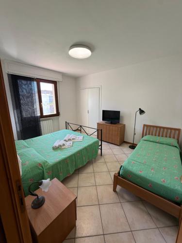 a bedroom with two beds and a table and a tv at Casa Serena in Donoratico