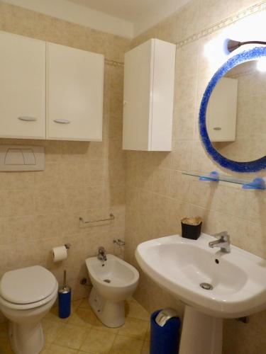 a bathroom with a sink and a toilet and a mirror at Casa Serena in Donoratico