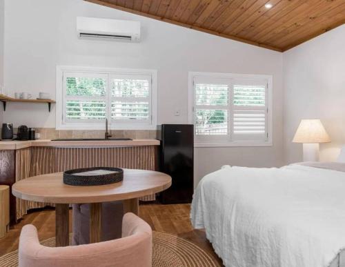 a bedroom with a bed and a table and a kitchen at Sanctuary Spaces - Sunset Bungalow 101 in Byron Bay