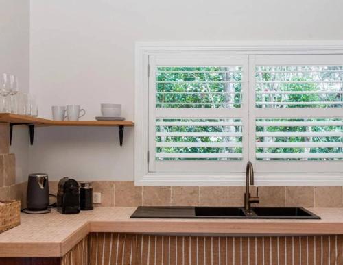 a kitchen with a sink and a window at Sanctuary Spaces - Sunset Bungalow 101 in Byron Bay