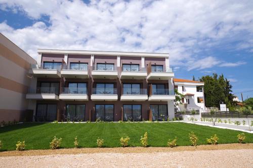 a building with a lawn in front of it at Sithonian Sunset Luxury Apartments in Skála Nikíta