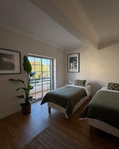 a bedroom with two beds and a potted plant at The Salty Nap in Ericeira