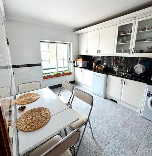 a kitchen with white cabinets and a table and chairs at The Salty Nap in Ericeira