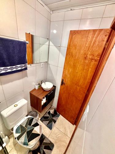 a small bathroom with a toilet and a wooden door at Refúgio da Serra - Apto Completo a 3 minutos do centro de Canela in Canela