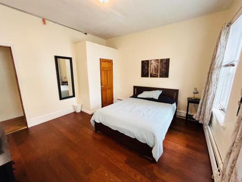 a bedroom with a white bed and a wooden floor at Apartments near Whole Foods, Brown University, Miriam, Downtown in Providence