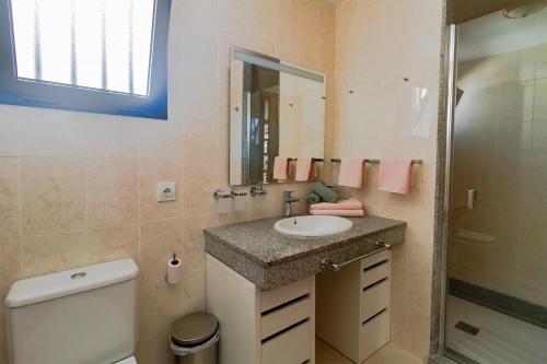 a bathroom with a sink and a toilet and a mirror at Niteo House in Costa Teguise