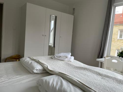 a white bedroom with a bed and a mirror at Ruddbecksgatan AA in Eskilstuna