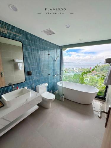a bathroom with a tub and a toilet and a sink at Flamingo Hai Tien Beach Resort in Thanh Hóa