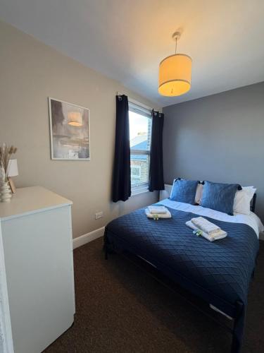 a bedroom with a bed with blue sheets and a window at Elegant Flat in Ealing in Greenford
