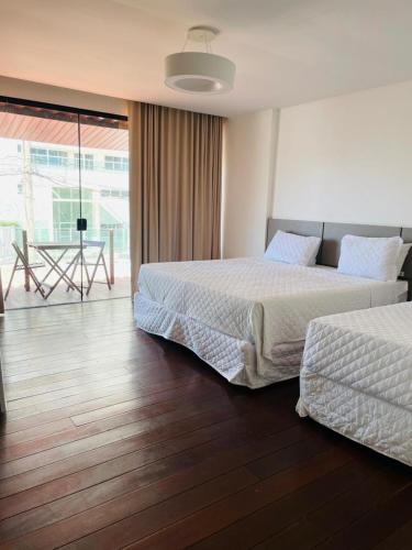 a bedroom with two beds and a table and a balcony at Transcar Suítes in Aracaju