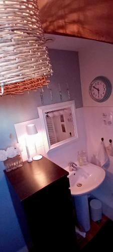 a bathroom with a sink and a clock on the wall at Chez ISA chambre chez l'habitant Léa in Montlouis-sur-Loire