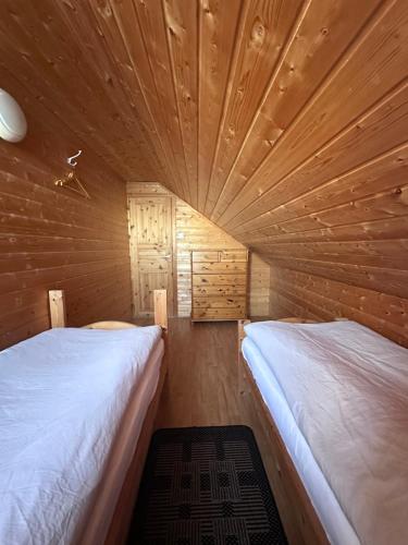 a bedroom with two beds in a wooden cabin at Lysbøen Bua in Ramberg