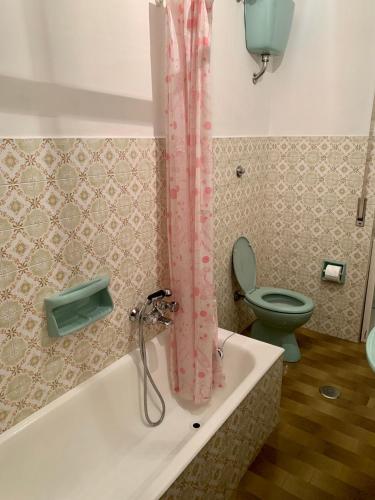 a bathroom with a tub with a toilet and a shower curtain at La casa di Amina in Rome