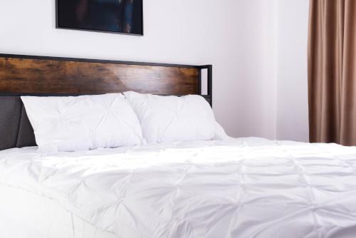 a bed with white sheets and a wooden headboard at Ghetto Experience - Self Check-In - Usa cu Cod in Vaslui