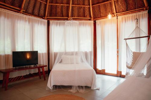 a bedroom with a bed and a tv and windows at Zirwa Hotel Boutique - Dentro del Parque Tayrona in El Zaino