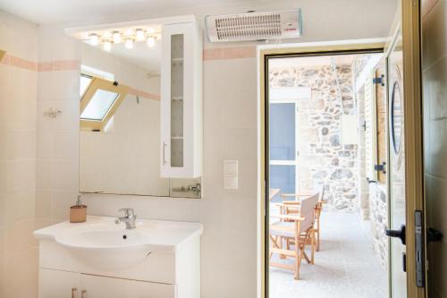 a bathroom with a sink and a mirror and a table at Oliva Mare I in Agia Fotia