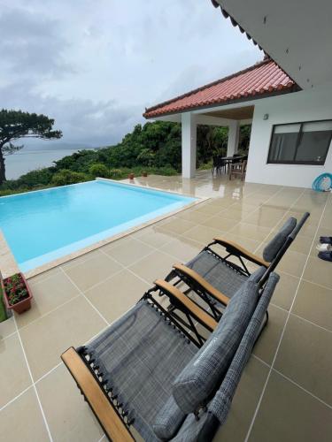 two lounge chairs sitting next to a swimming pool at 呼吸する宿 ISHIGAKI Tida in Ishigaki Island