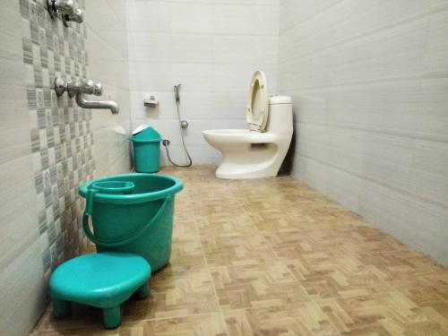 a bathroom with a toilet and a green stool at corbett motel in Rāmnagar