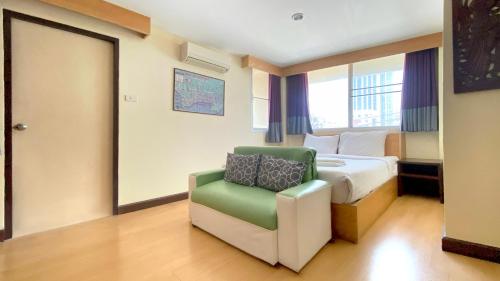 a hotel room with a bed and a green chair at Sea Place Pattaya Soi 7 in Pattaya