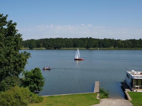 a sail boat on a large lake with a house at Ruppiner Seeblick Ferienwohnungen in Neuruppin