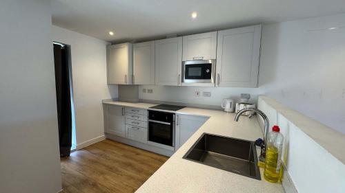 a kitchen with white cabinets and a sink at Joyful Management - A Mordern Semi-Detached House with 3 bedroom in Manchester