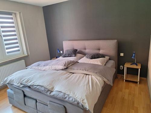 a large bed in a bedroom with a gray wall at Fewo Holtwicker Ei in Rosendahl