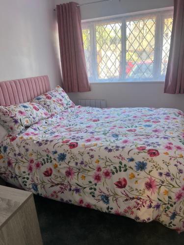 a bed with a floral comforter in a bedroom at Newly refurbished Annexe in Wareham