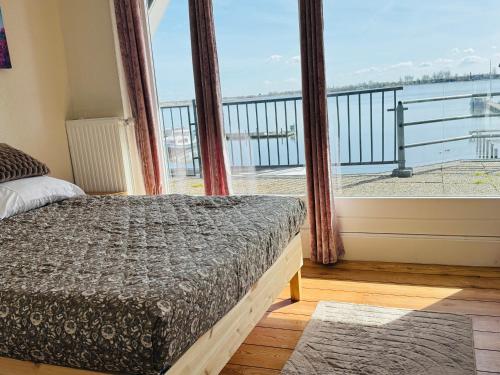 a bedroom with a bed and a large window at Weromerie Premium Hotel and Apartment in Wormer