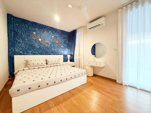 a bedroom with a white bed and a blue wall at THE MAISON Phuket in Ban Lo Long