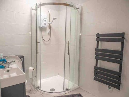 a shower with a glass door next to a sink at Cwm Ffernol in Machynlleth