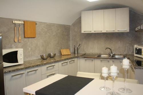 a kitchen with white cabinets and a table with a microwave at Cal Arxè in Besalú