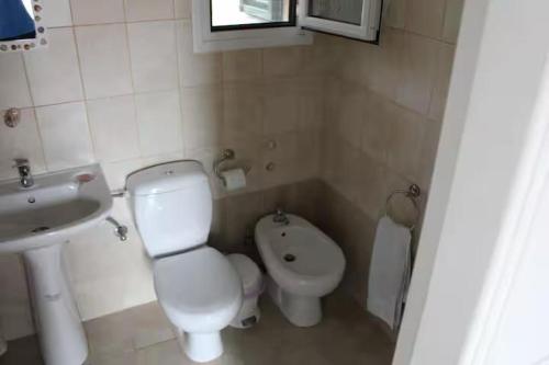 a small bathroom with a toilet and a sink at Lilac House Kefalonia in Ratzaklíon