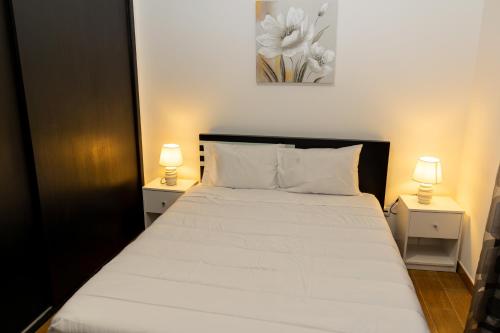 a bedroom with a white bed with two lamps at Furnas Panorama House in Furnas