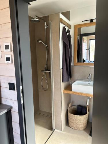 a bathroom with a shower and a sink at Lykke Huus Tinyhaus an der Nordsee mit Fasssauna in Schweiburg