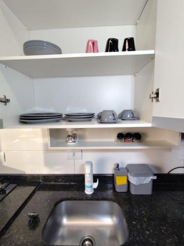 eine Küchenspüle mit Tellern und Schüsseln auf Regalen in der Unterkunft Apartamento em Maringá zona 07, próximo da universidade UEM in Maringá