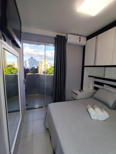 ein Schlafzimmer mit einem Bett und einem großen Fenster in der Unterkunft Apartamento em Maringá zona 07, próximo da universidade UEM in Maringá