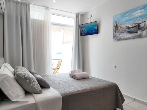 a bedroom with a bed with a window and avertisement at Captain's Tolo Sea View 2 in Tolo