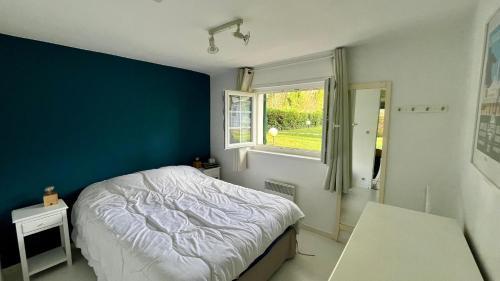 a bedroom with a bed and a blue wall at Le Lodge du Touquet in Le Touquet-Paris-Plage