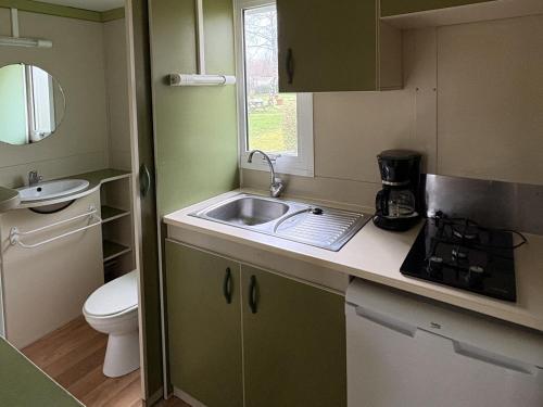 a small kitchen with a sink and a toilet at Camping Le Neptune in Lanloup