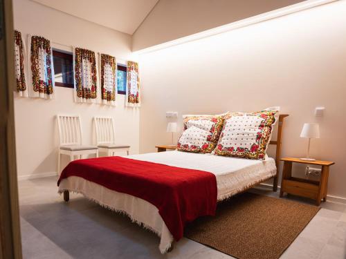 a bedroom with a bed with a red blanket and pillows at Quinta de Segade in Santa Marta